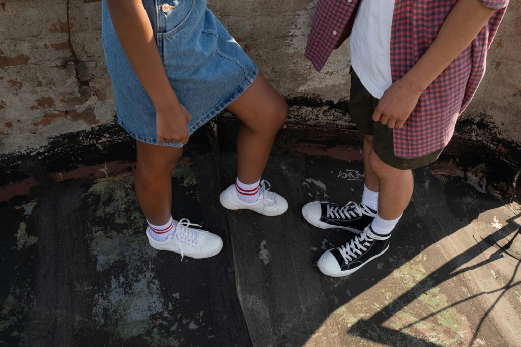 Close-up of teens wearing casual outfits and sneakers in an urban setting.
